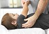 Physical therapist stretching a child's upper back