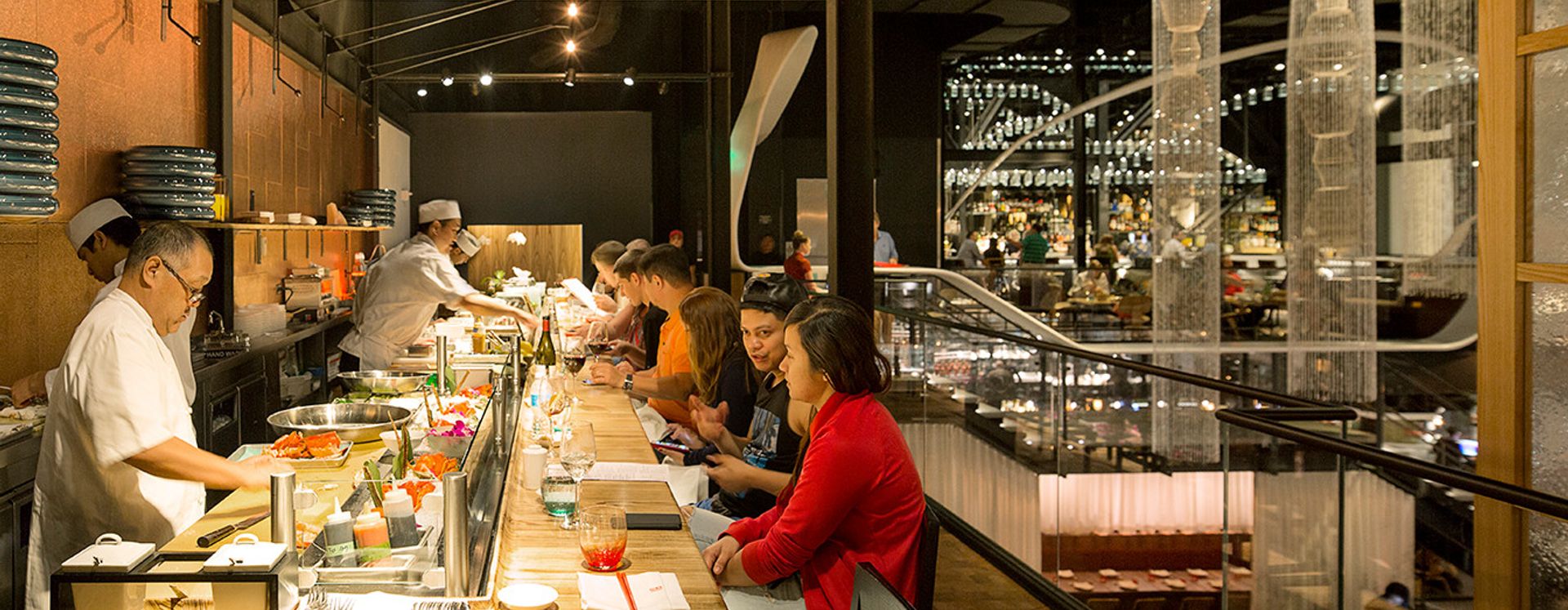 people eating at sushi bar at morimoto asia restaurant in disney