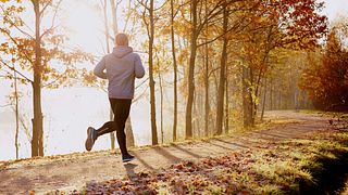 Man running in park at autumn morning