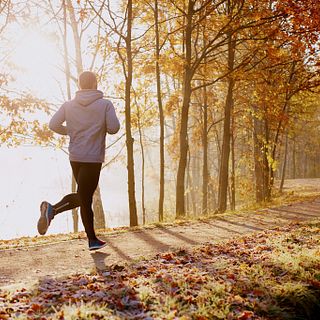 Man running in park at autumn morning