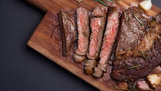 Grilled rib-eye steak of marble beef closeup with spices on a wooden Board. Juicy steak medium sliced and ready to eat. With copy space
