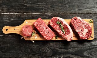 Fresh raw Prime Black Angus beef steaks on wooden board