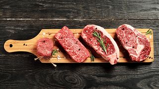 Fresh raw Prime Black Angus beef steaks on wooden board