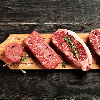 Fresh raw Prime Black Angus beef steaks on wooden board
