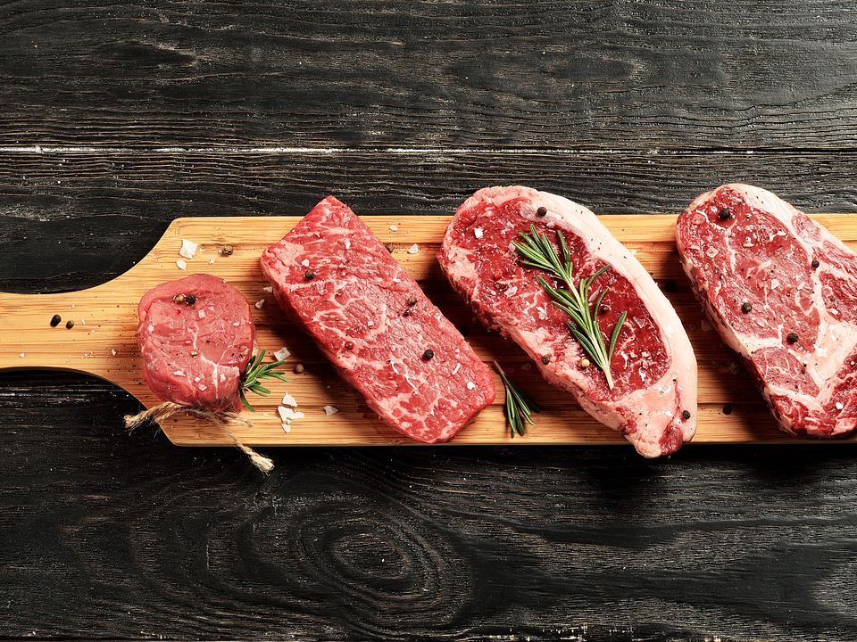 Fresh raw Prime Black Angus beef steaks on wooden board