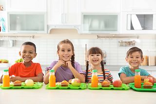 Children sitting at table and eating healthy food during break at school