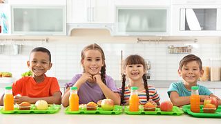 Children sitting at table and eating healthy food during break at school