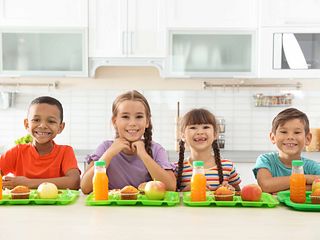 Children sitting at table and eating healthy food during break at school