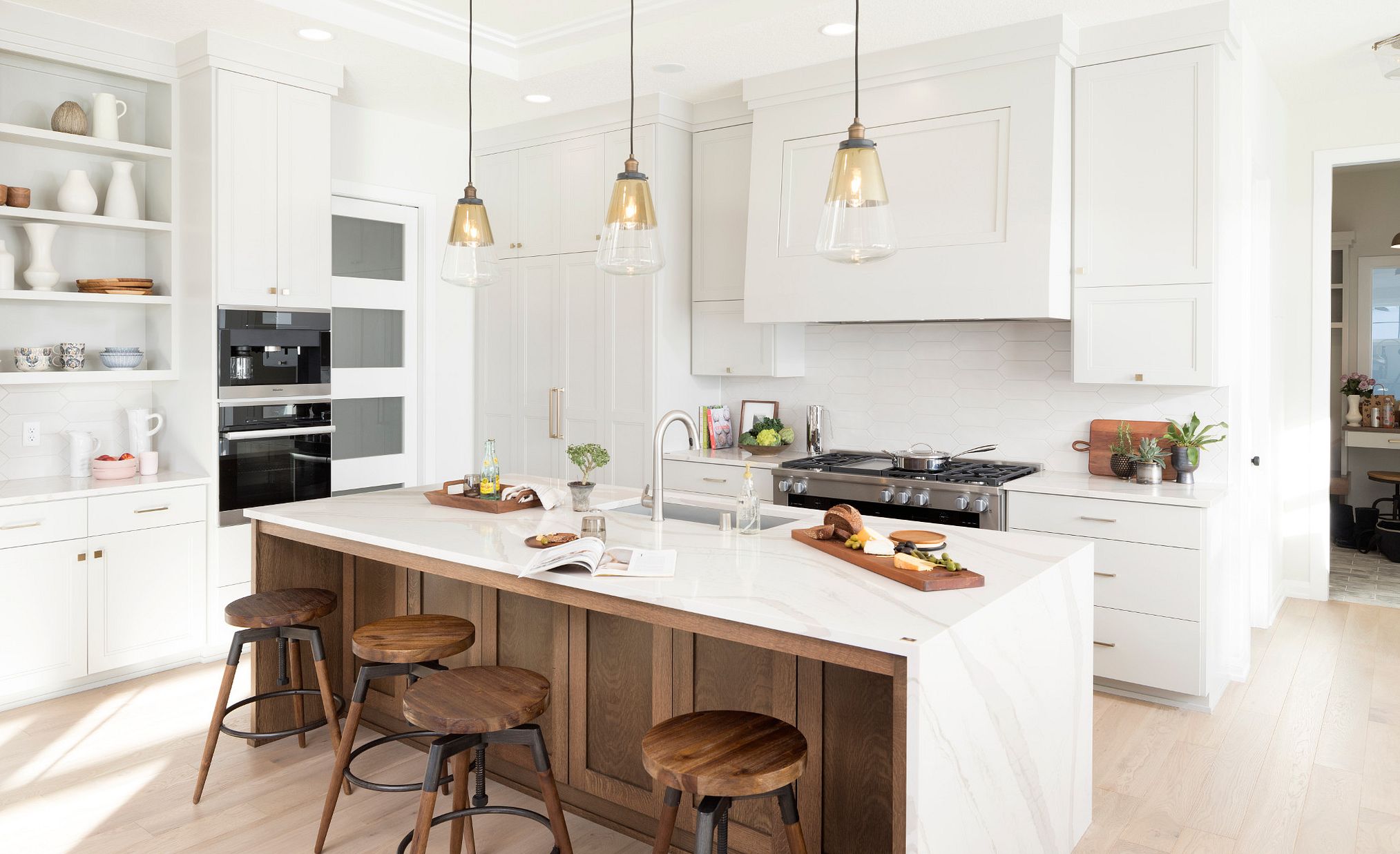 White marble-look quartz countertops in a kitchen with white and medium wood toned cabinets.
