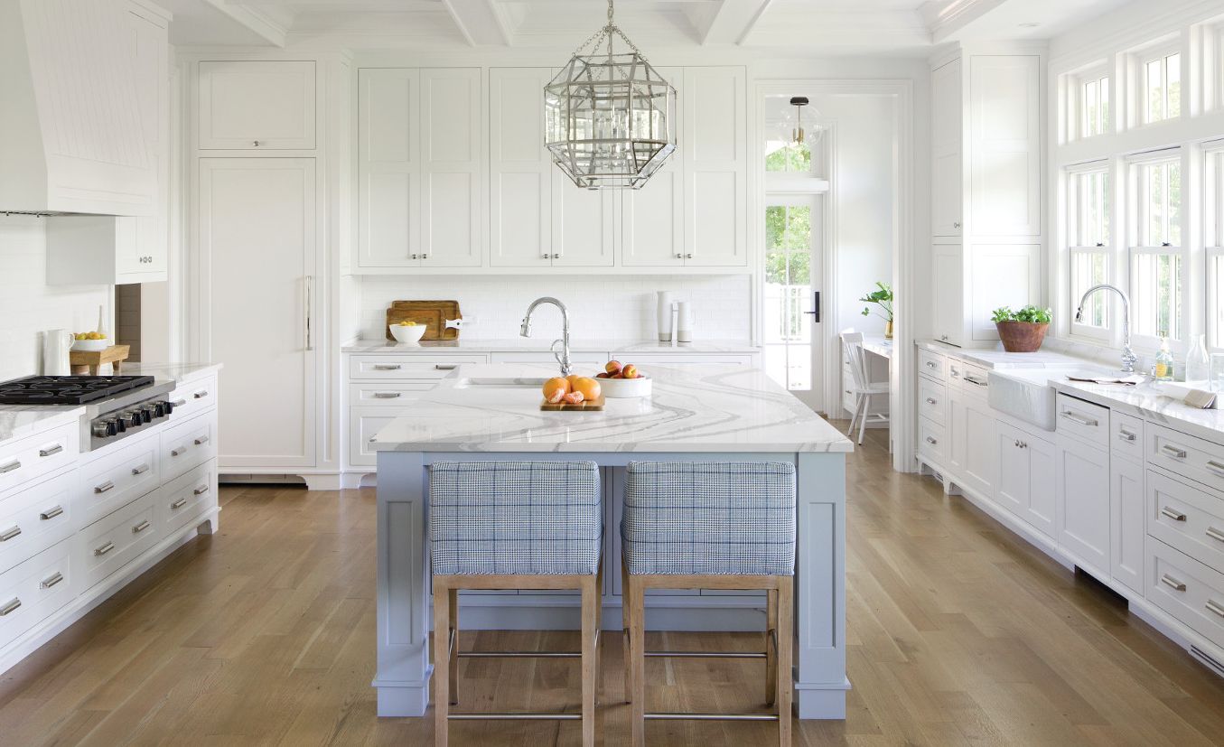 White kitchen with light blue-gray island and Cambria Brittanicca countertops.
