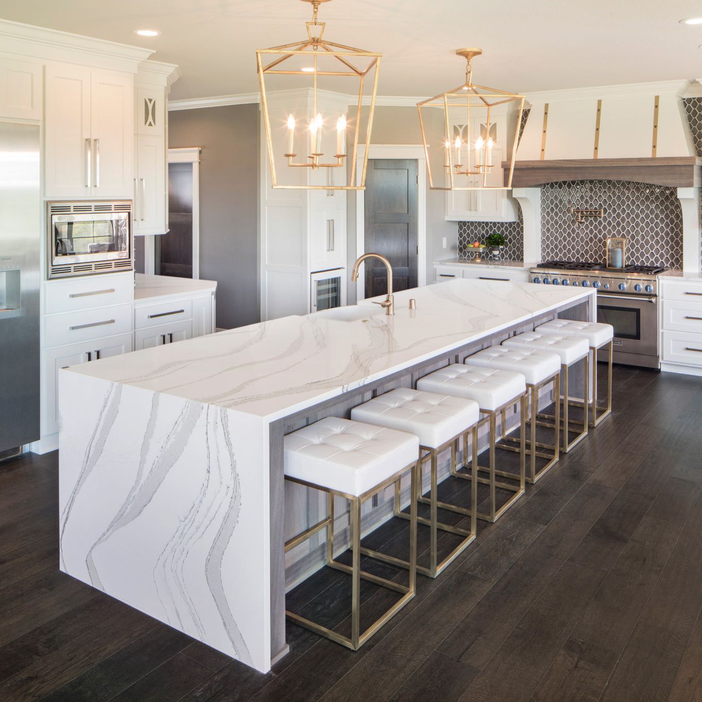 White marble-look quartz countertops in a white and gold kitchen.