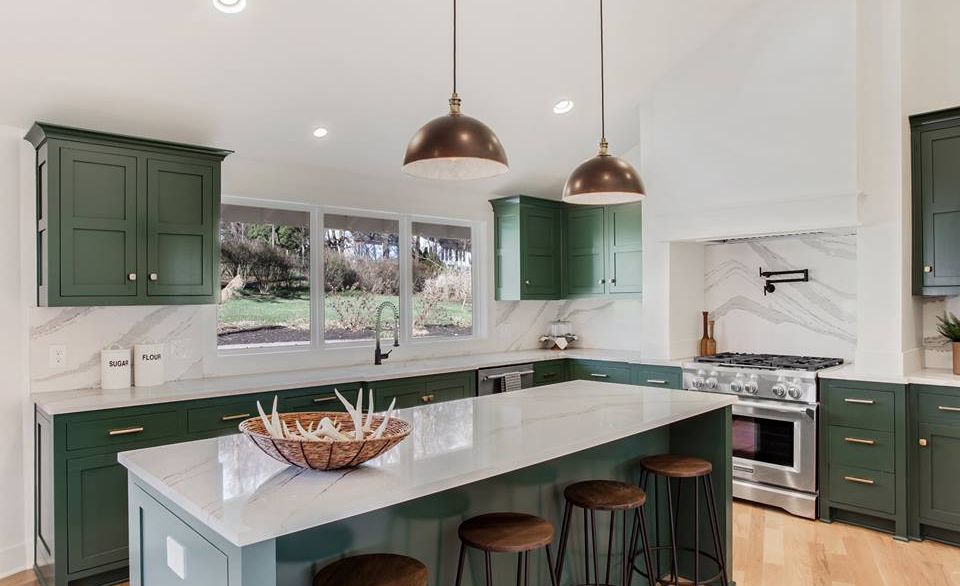 Cambria Brittanicca™ backsplash and countertops contrast emerald green cabinets in this chic farmhouse kitchen.