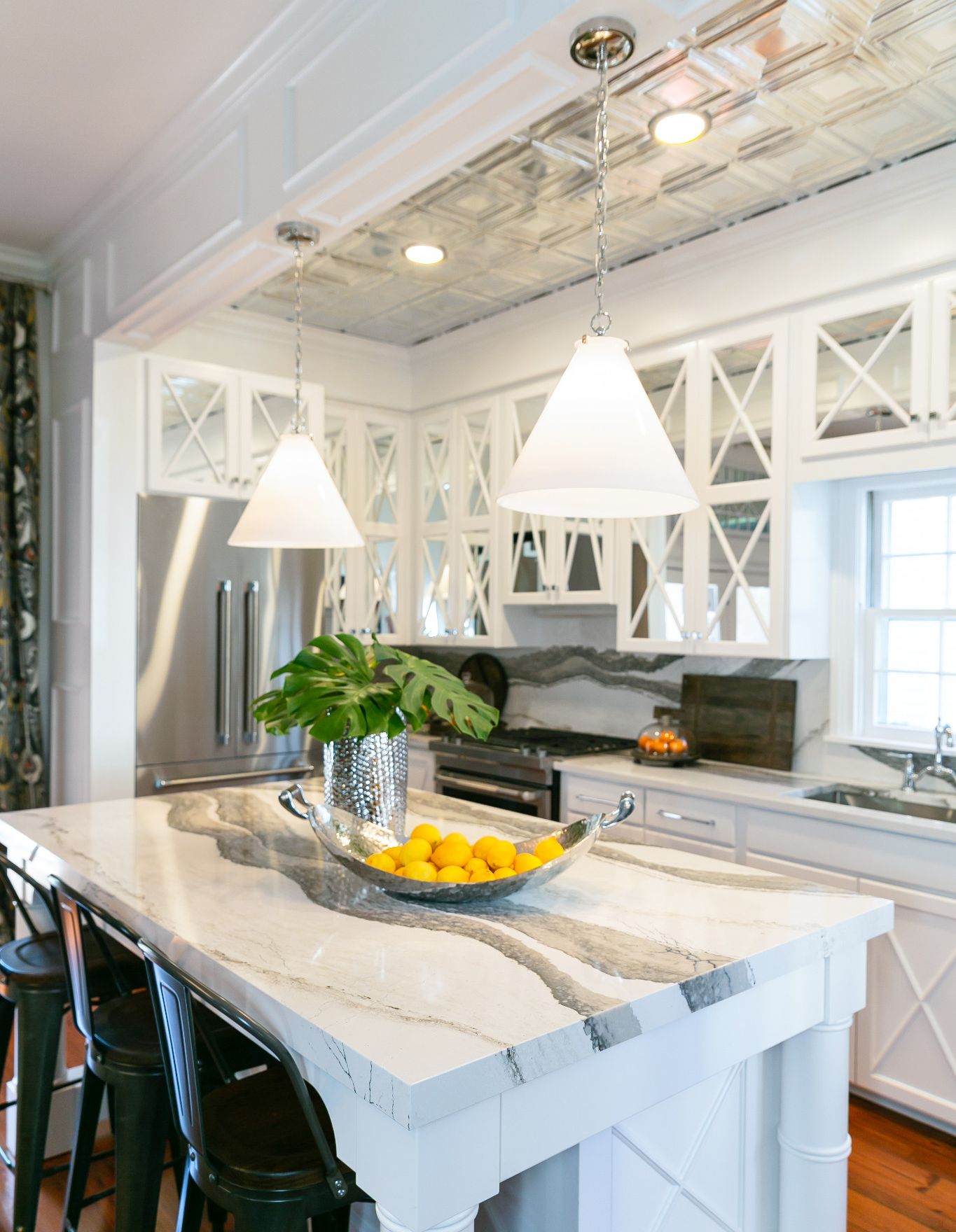 A white kitchen with mirrored cabinet doors with Cambria Skara Brae countertops and backsplash.
