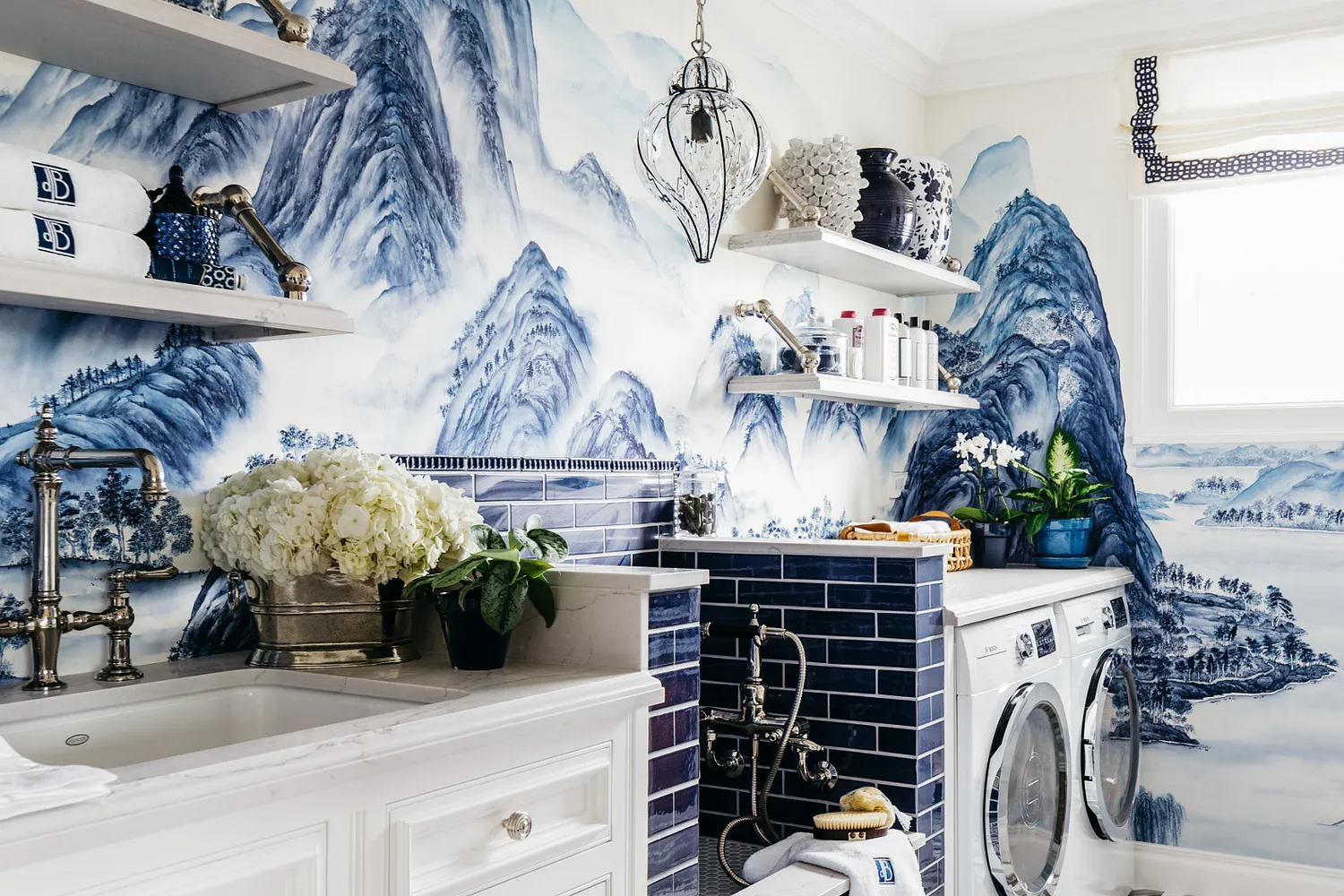 a blue and white themed laundry room featuring Cambria Ella quartz countertops, shelving, and a dog shower with a gorgeous blue mountain mural on the wall.