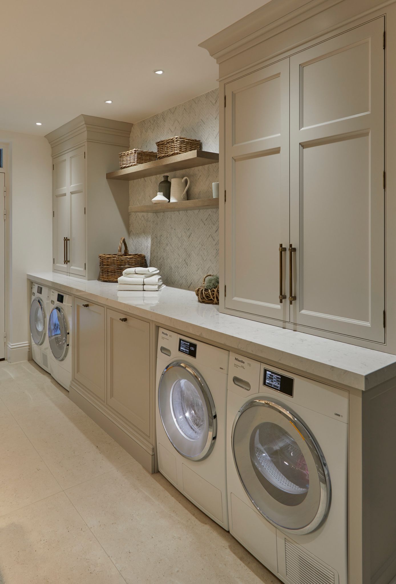 A second view of a laundry room with cream cabinets and marble chevron tile paired with Camrbia Swanbridge countertops.