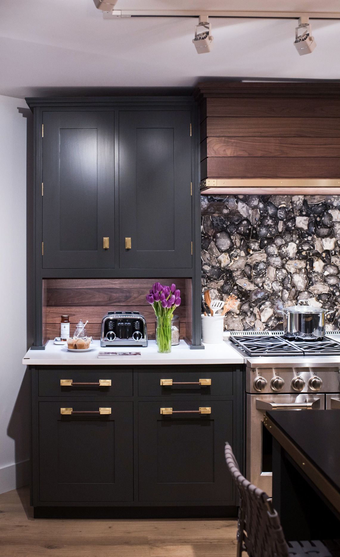 A custom mosaic of English flint pairs well with olive green cabinets, walnut, and Cambria White Cliff Matte.