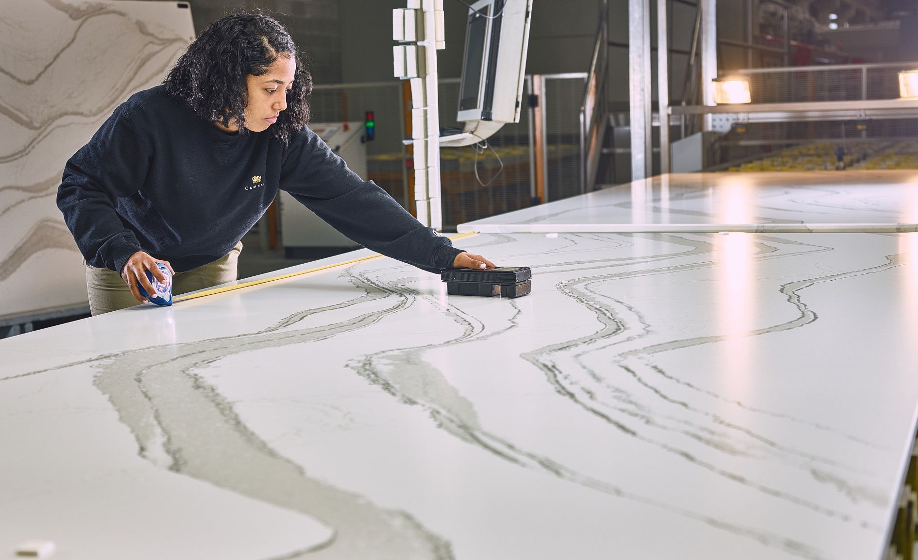 A Cambria employee uses a tool to measure gloss levels on a Cambria slab.