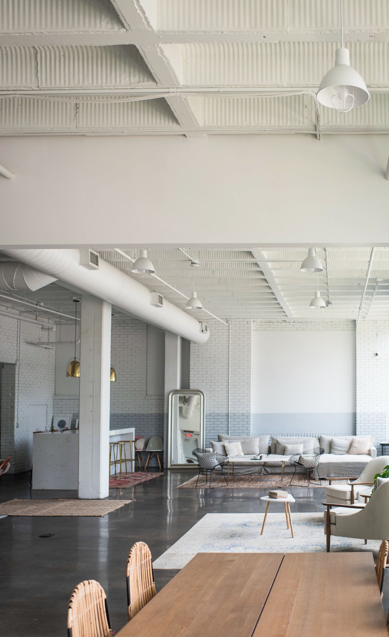 Exposed beams, pipes, and concrete flooring reflect the building’s industrial roots.