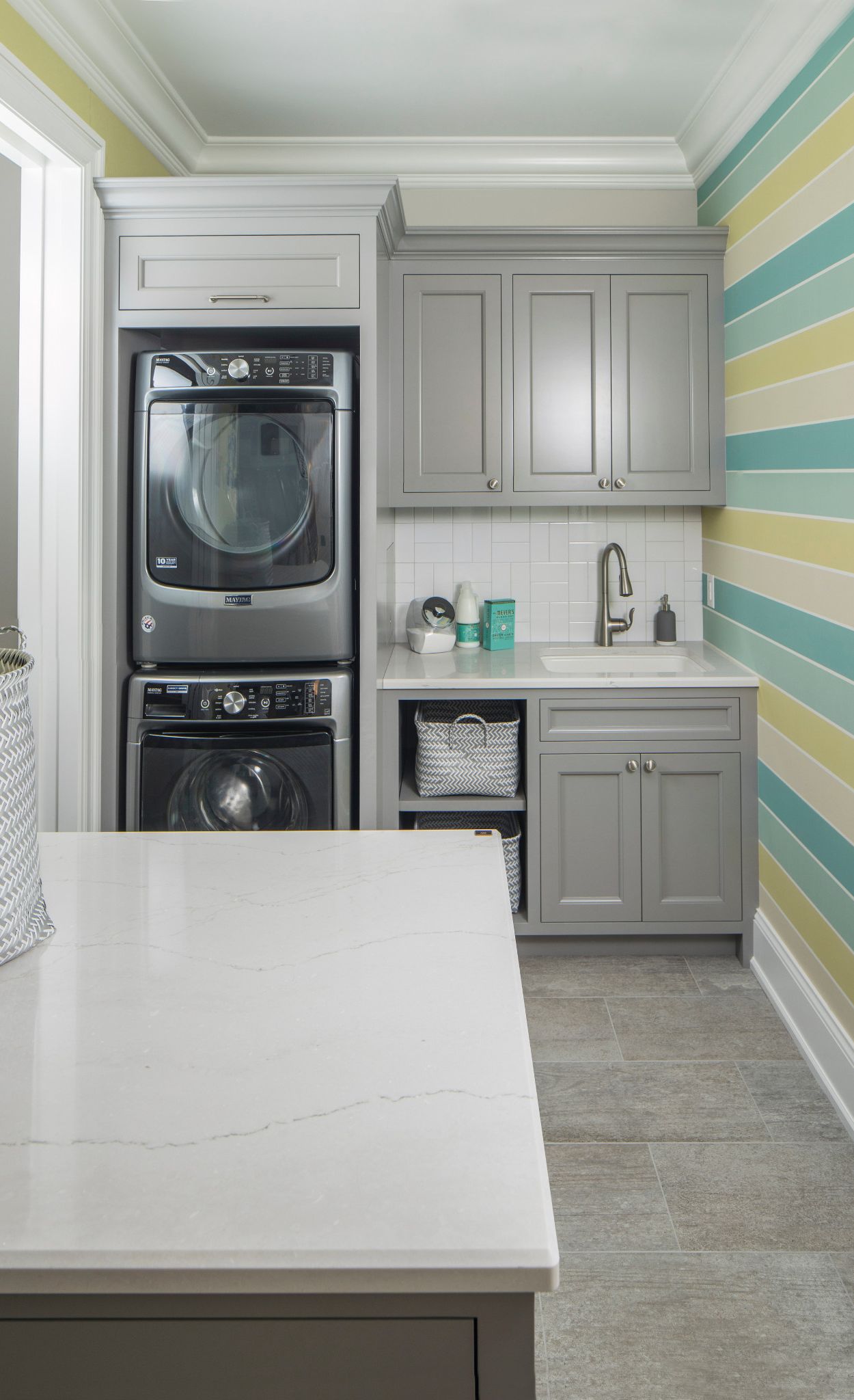 Cambria Ella in a laundry room with blue and green striped walls and gray countertops.