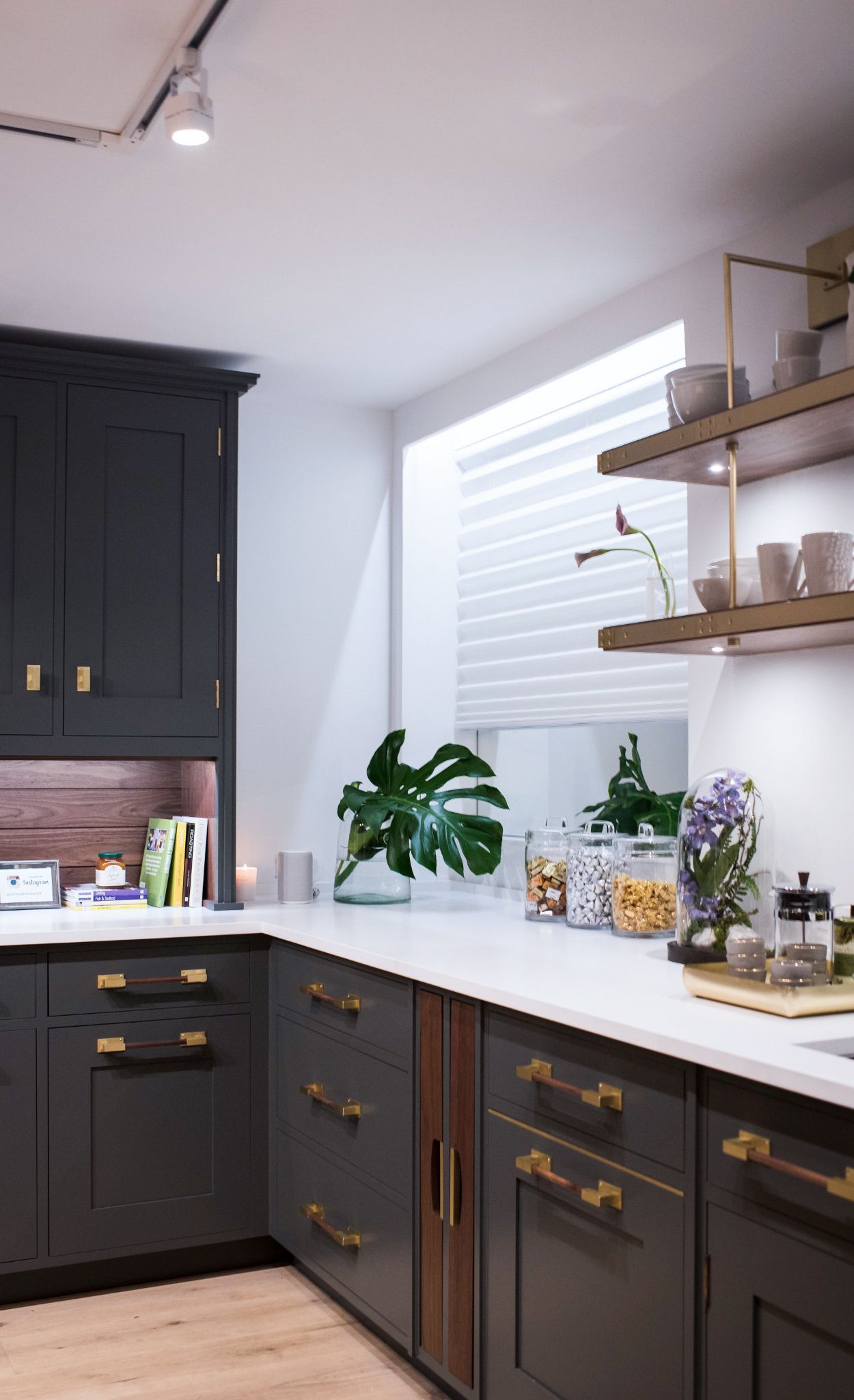 Olive green cabinetry paired with Cambria White Cliff Matte countertops, brass hardware, and open shelving.