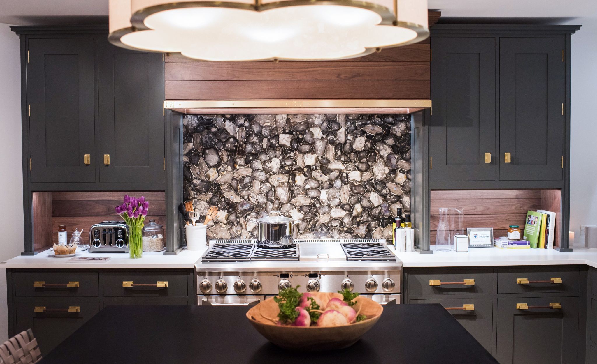 Brass accents create elegant and cohesive kitchen motif, from the hardware to the range hood and light fixture.