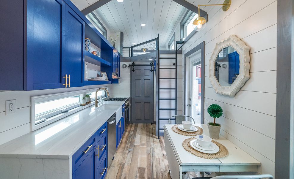 Small space kitchen with cobalt blue cabinets, Cambria Ella countertops, and white shiplap ceiling and walls. 