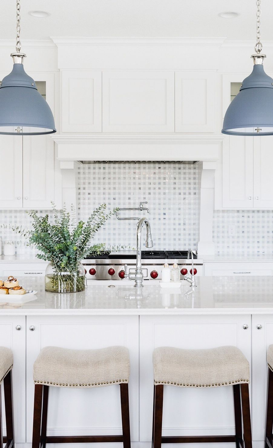Cambria Swanbridge countertops in a white kitchen with matte blue light fixtures