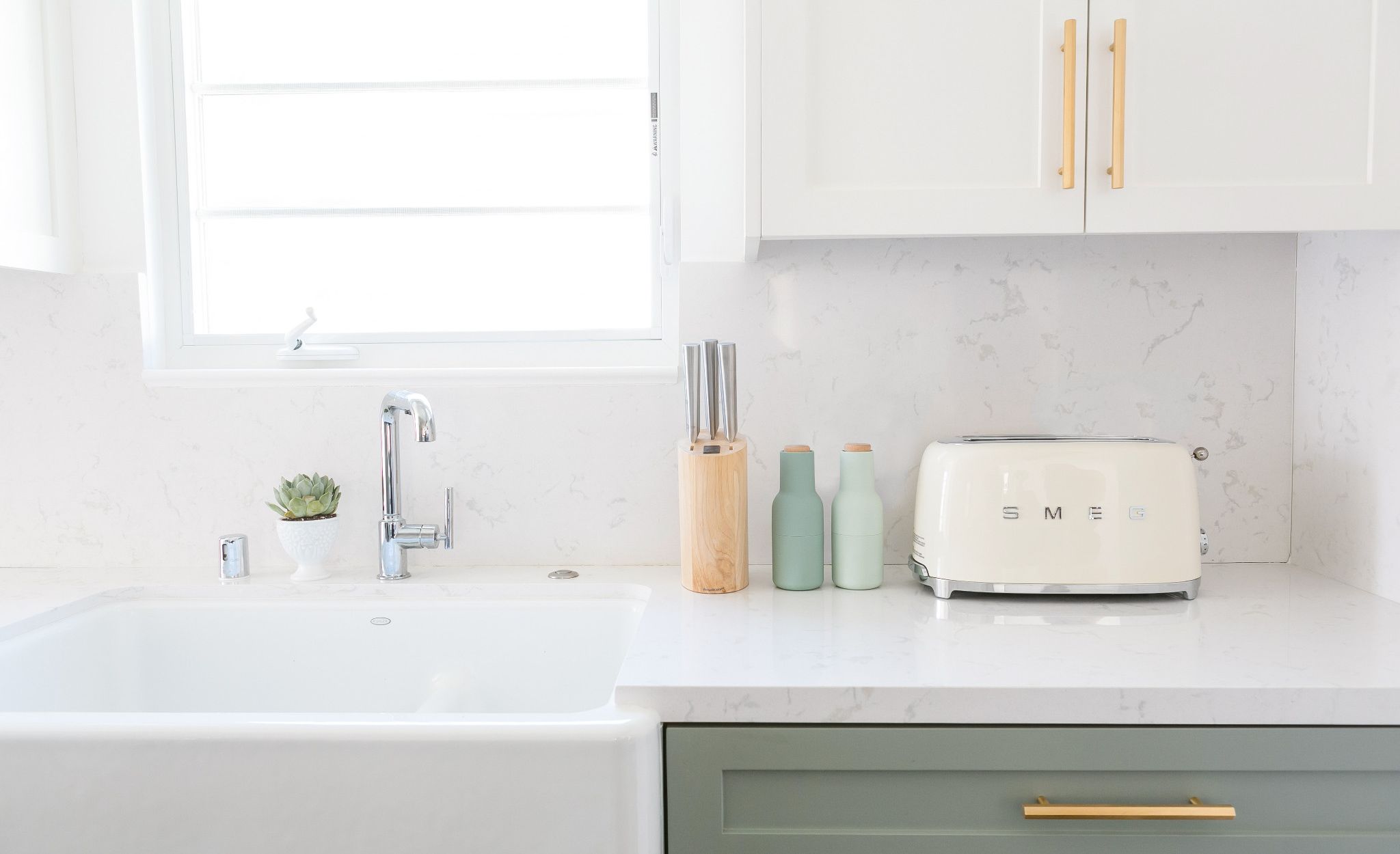 Cambria Torquay’s marbled beauty creates a serene palette paired with sage cabinets and mixed metals this green and white kitchen.