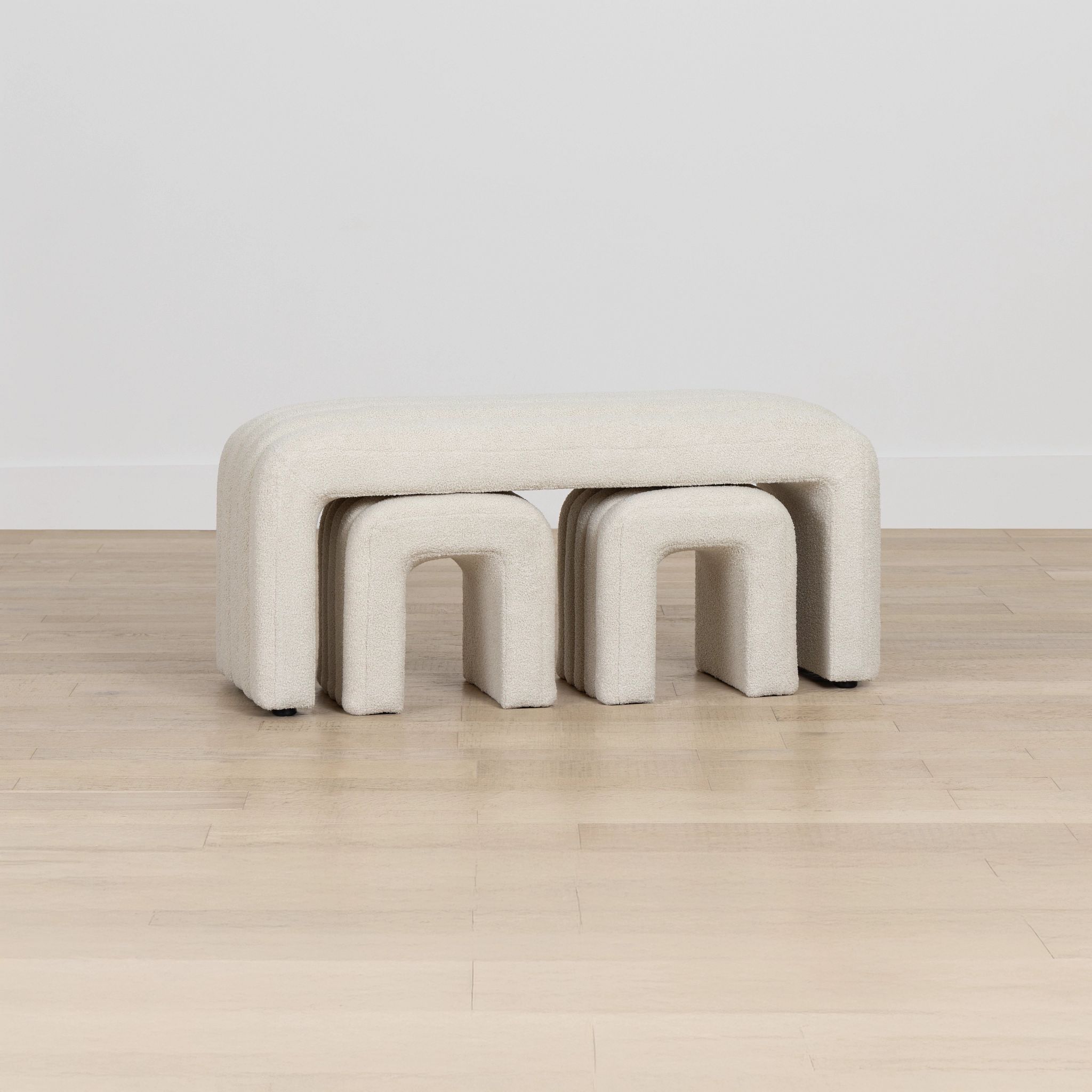 Beige bench with three curved sections on a wooden floor.