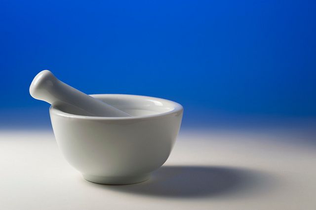 White porcelain mortar and pestle against blue background