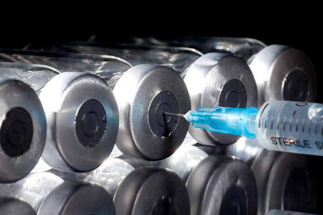 A vaccine candidate is injected by a syringe into a vial for vaccine development.