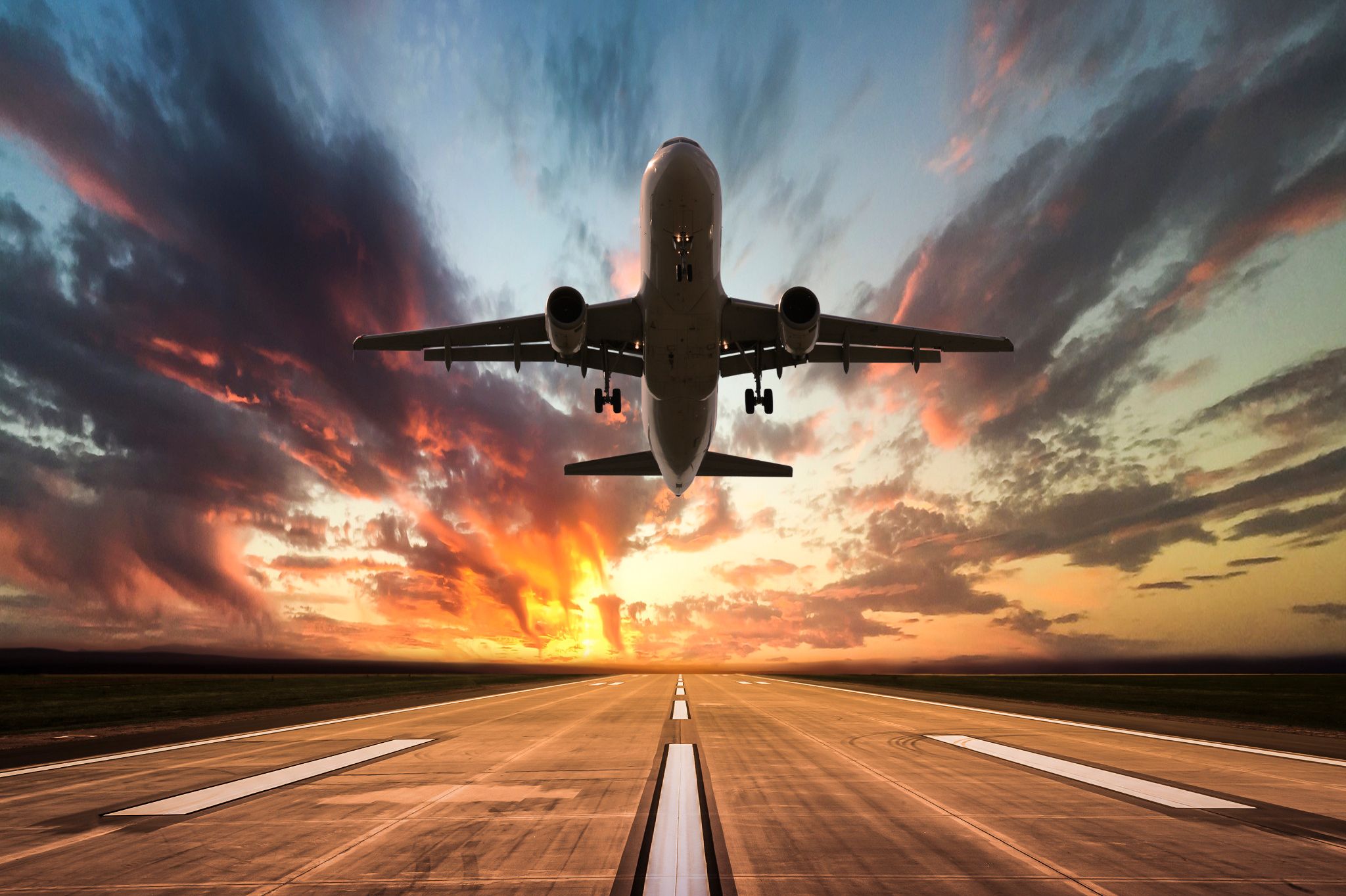 airplane taking flight, as seen from airport runway below