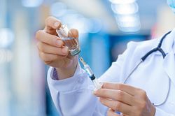 Photo of a technician holding a vial of a vaccine and syringe.