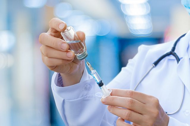 doctor in white lab coat holding vaccine bottle and syringe