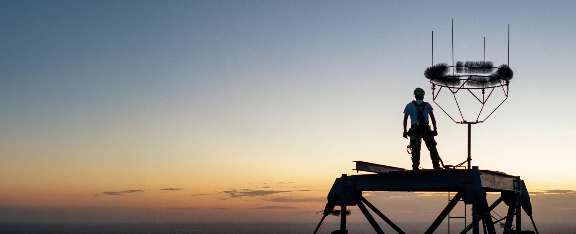 Man standing on large tower overlooking the sunset on the horizon