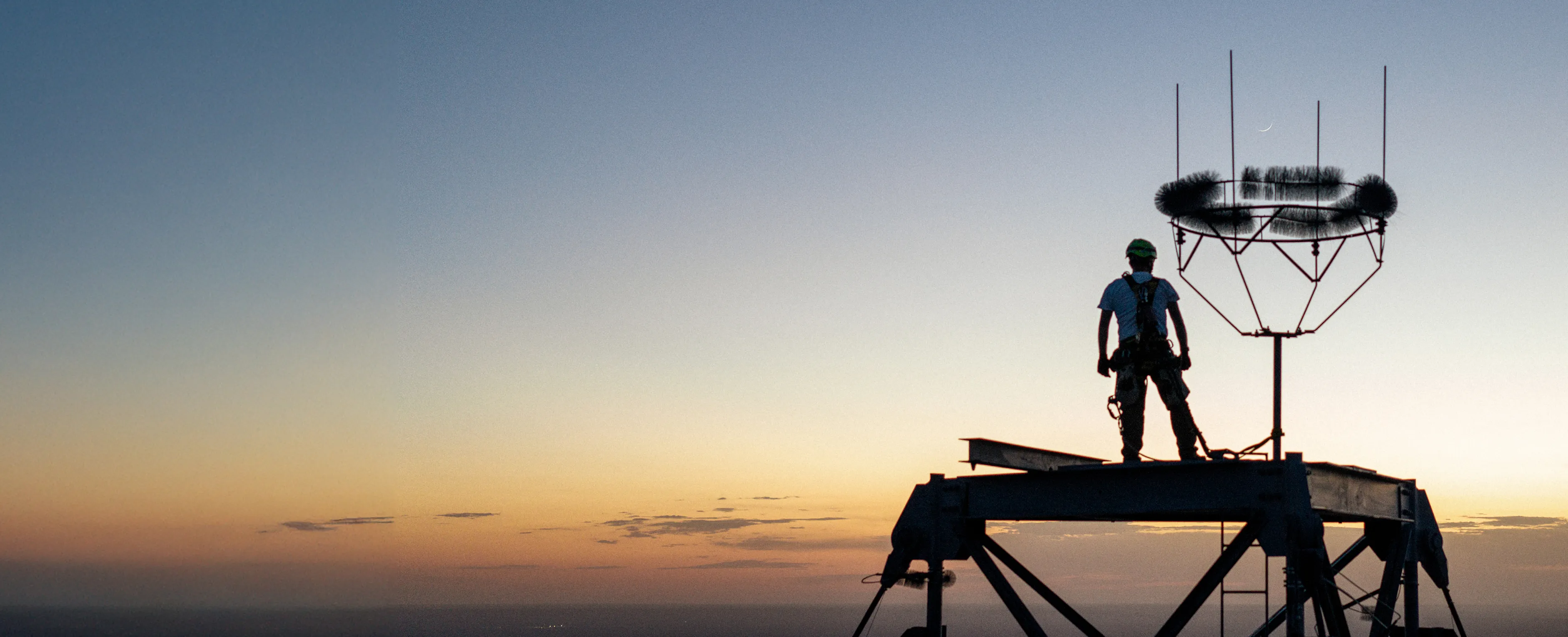Man standing on large tower overlooking the sunset on the horizon