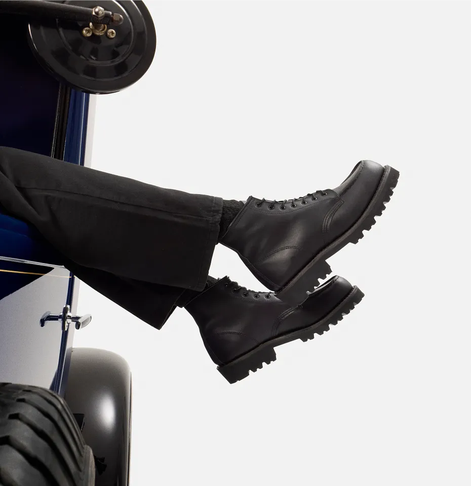 Sideview of a car against a white background with a person's legs hanging out 