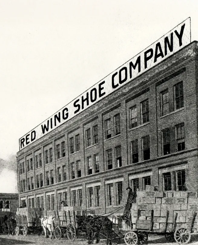 Historical photo of the Red Wing Shoe Company building with horse-drawn carriages in front