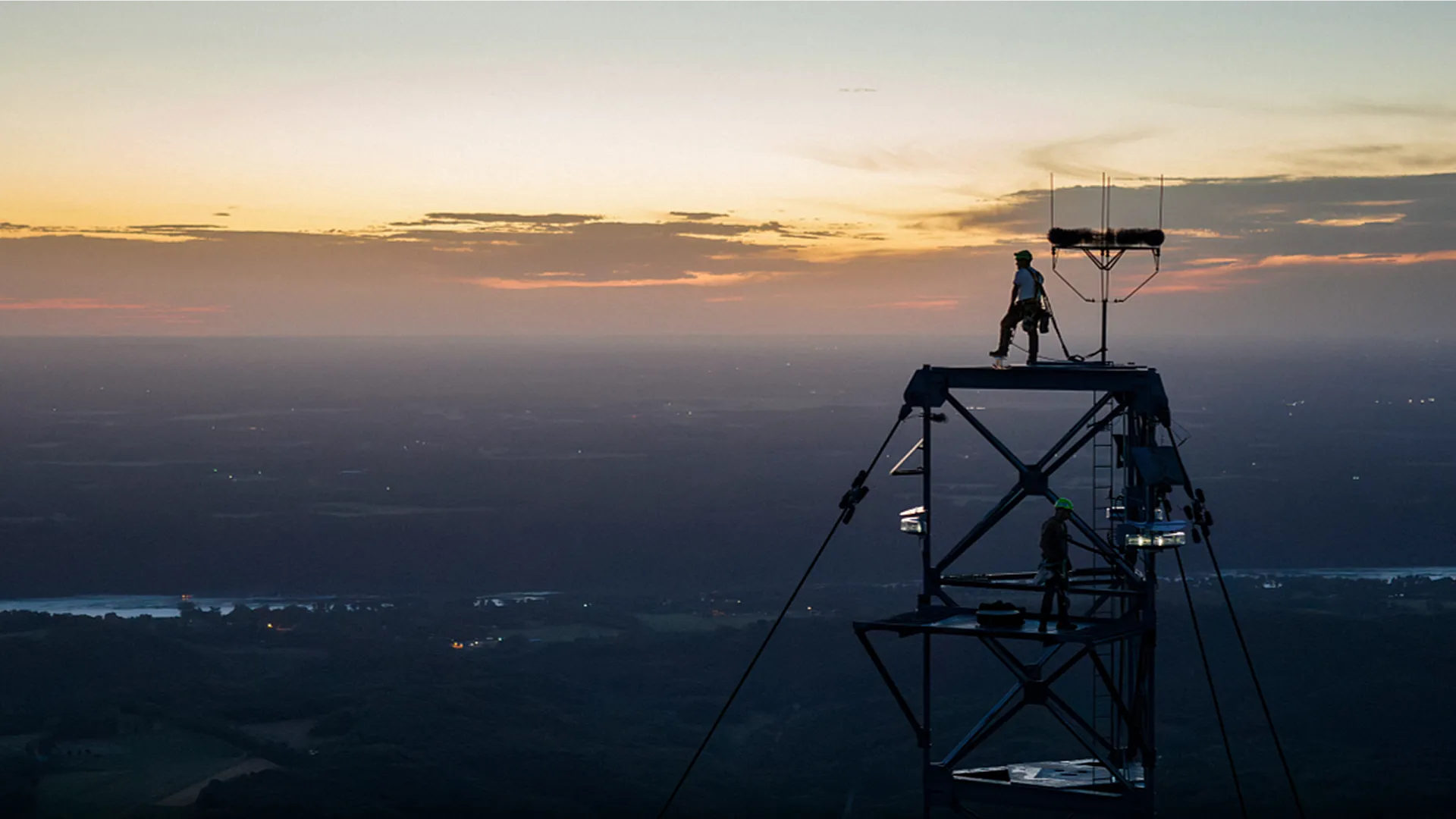 Aerial view of two men on the top of a tower overlooking a city