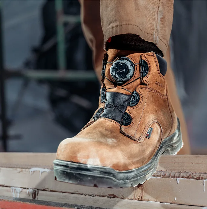 Close up of a person's foot wearing a King Toe boot, stepping on some boards