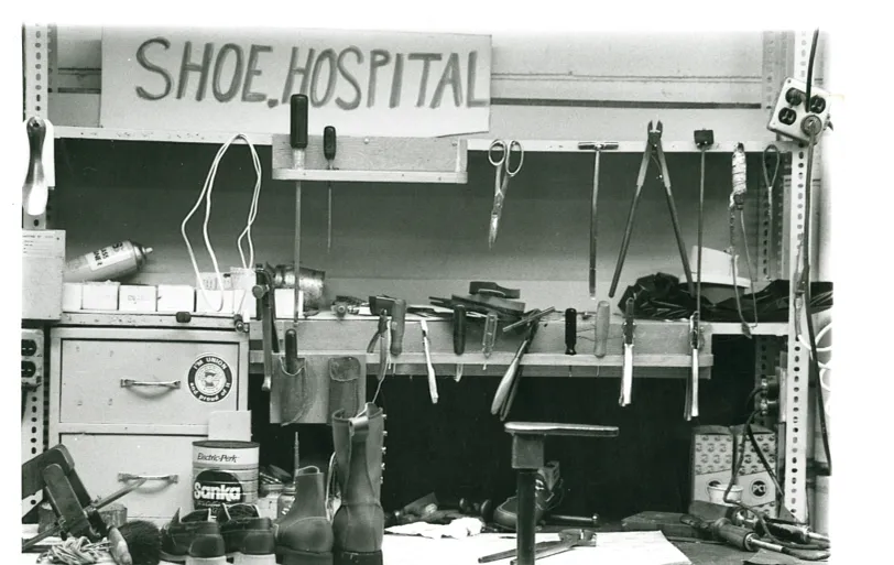 A boot repair workbench with boots and tools on it