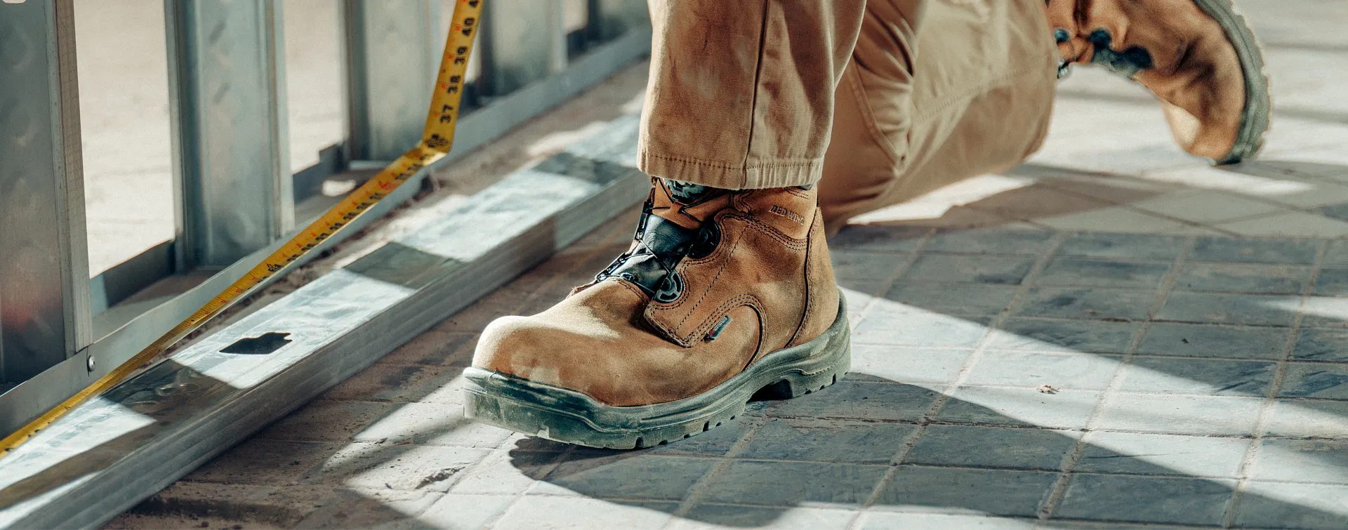 Close up of a King Toe boot worn by a person kneeling in a construction area
