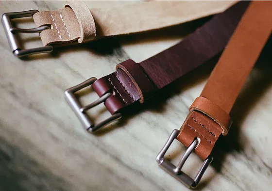 Close up view of the buckles of 3 Red Wing belts laying on a table
