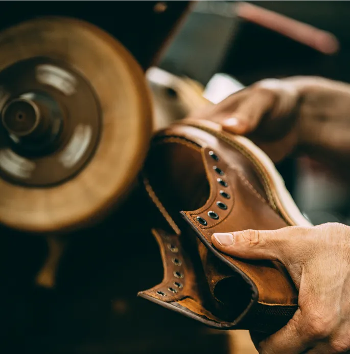 Close up of hands holding a boot to a polishing machine