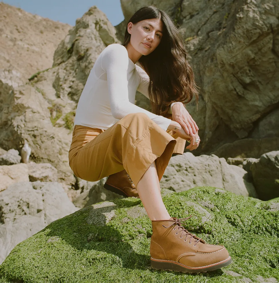 A woman crouching on a large boulder
