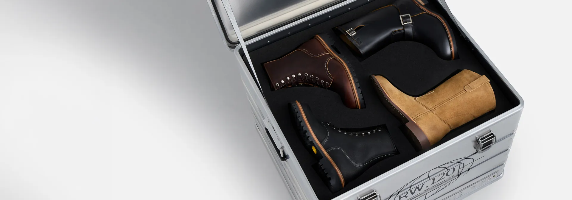 An open metal box against a white background that contains 4 different styles of Red Wing boots 
