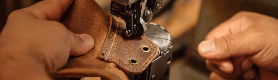 Close up of hands sewing a boot