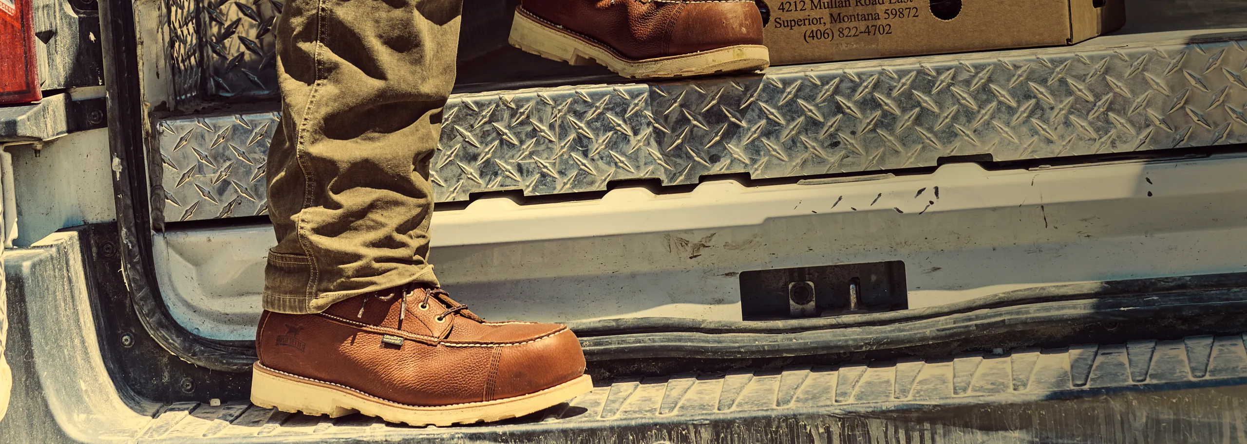 Close up of wingshooter boots that a person is wearing, standing in the back of a truck