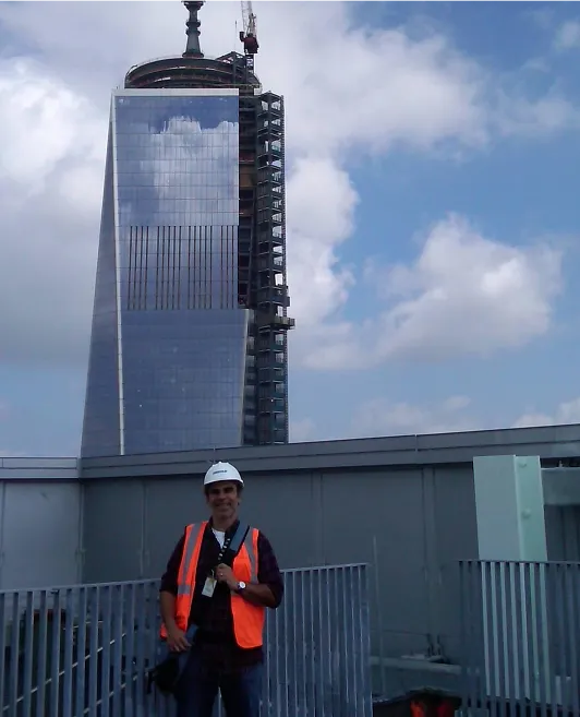 Miguel A. Rueda on the jobsite with a building under construction behind him