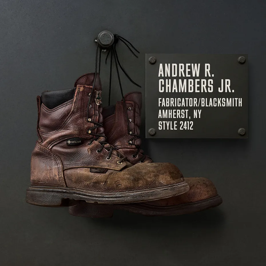 A pair of boots hanging on a black wall next to a plaque with information